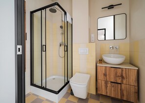 Ein modernes Badezimmer mit einer gläsernen Dusche, einem weißen Waschbecken und einem Holzmöbelkorpus.