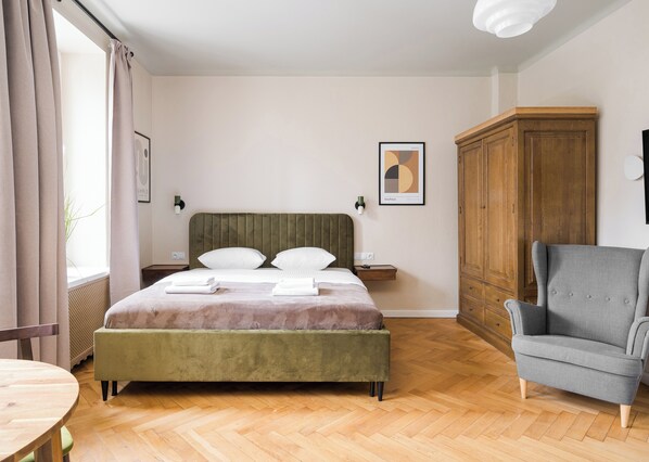 Ein Schlafzimmer mit einem Bett, einem Nachttisch, einem Kleiderschrank, einem Sessel und einem Tisch.