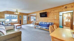 A wooden interior with a sofa, a TV mounted on the wall, and a dining table.