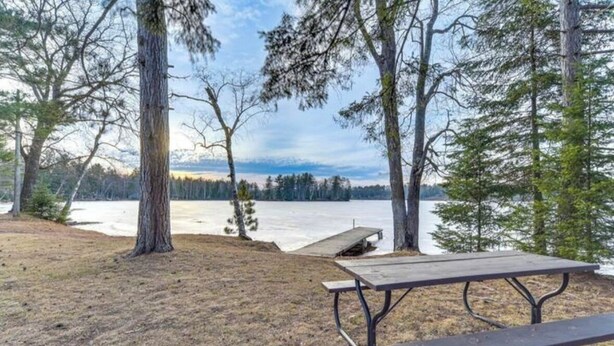 A picnic table in a forested area with a view of a lake.