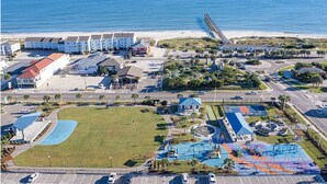 A coastal hotel with multiple buildings, a parking lot, a swimming pool, and a beach view. - Cozy 5BR-2.5BA Cottage on Canal, Private Heated Pool, Private Boat Dock (Ocean Isle Beach)