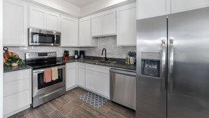 A modern kitchen with white cabinets, stainless steel appliances, a built-in microwave, and a dishwasher.