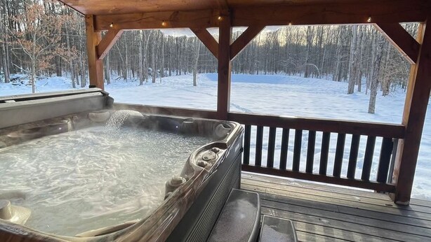 Una vasca idromassaggio su un pontile di legno con vista su una foresta innevata.