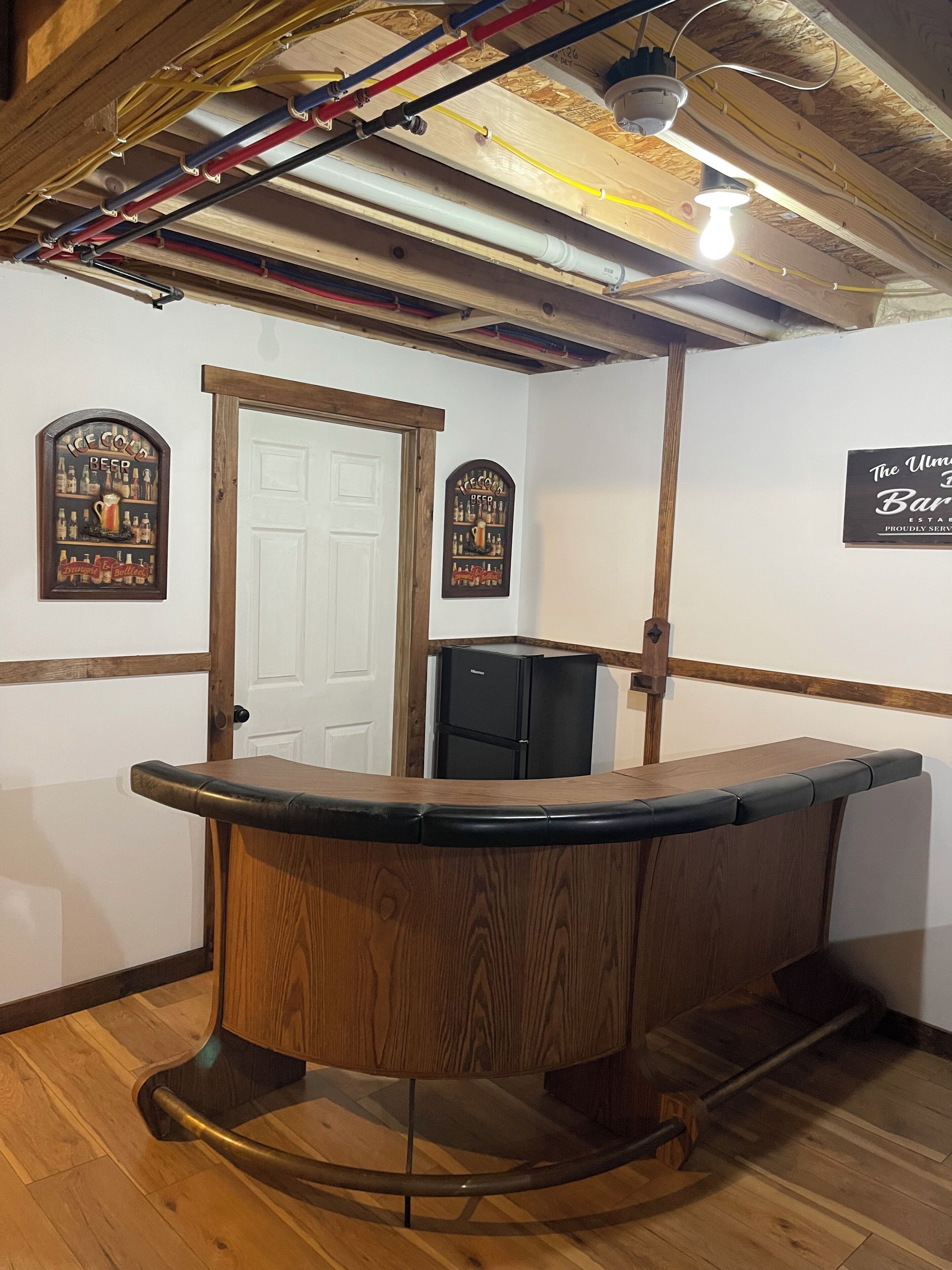 A bar area with wooden counter, wooden beams, and a white door.