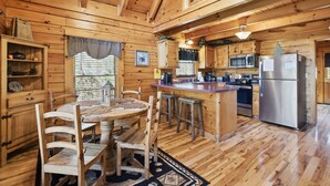 Een houten cabin met een eethoek, keuken en een groot raam.