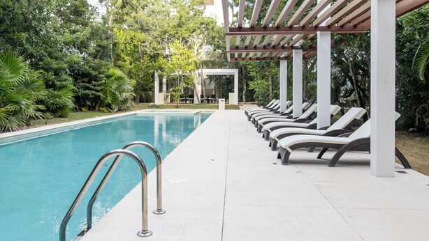 A swimming pool with lounge chairs and a pergola. - Modern Apt Tulum with 2 BDR Gym & Pool (Tulum)