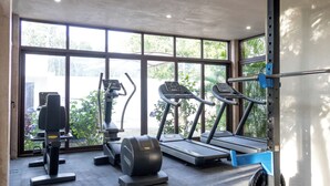 A gym with treadmills, an elliptical, and a weight bench. - Modern Apt Tulum with 2 BDR Gym & Pool (Tulum)