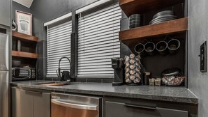 A modern kitchen with a dishwasher, a kettle, and a coffee maker. - The Iverson - Urban Core OKC (Oklahoma City)