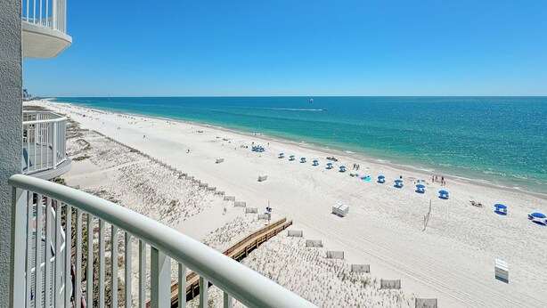 Ein Strand mit einer Holzpromenade, Strandzelten und einem klaren, blauen Himmel.
