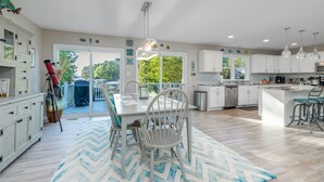 A modern kitchen with white cabinets, a dining area with a white table and chairs, and a large window providing a view of the outdoors. - New! Lake, Dock, Pool Table, Firepit, Deck, Yard, Firepit (Henrico)