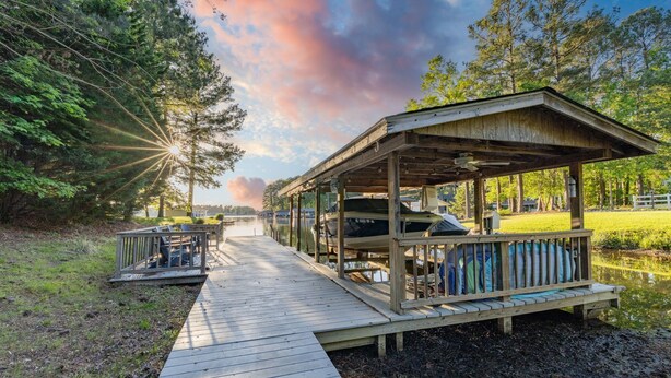 A wooden deck leading to a covered pavilion with seating and a view of a lake. - New! Lake, Dock, Pool Table, Firepit, Deck, Yard, Firepit (Henrico)