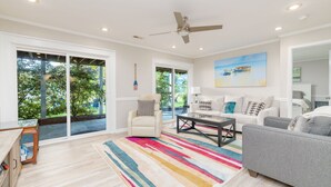 A spacious living room with a large window, a ceiling fan, and a colorful striped rug. - New! Lake, Dock, Pool Table, Firepit, Deck, Yard, Firepit (Henrico)