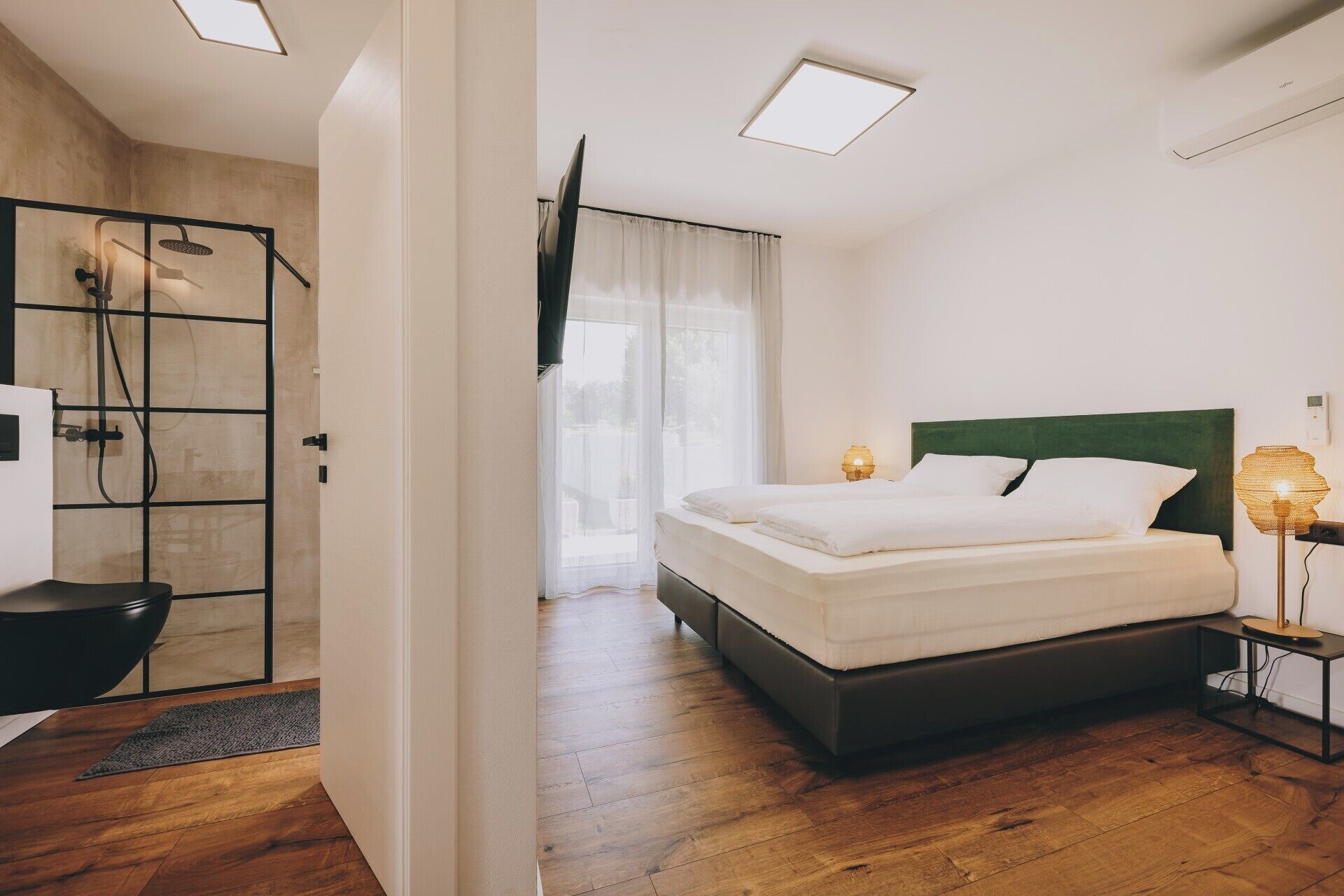Una camera da letto moderna con un letto grande, una doccia idromassaggio e vista sull'esterno.