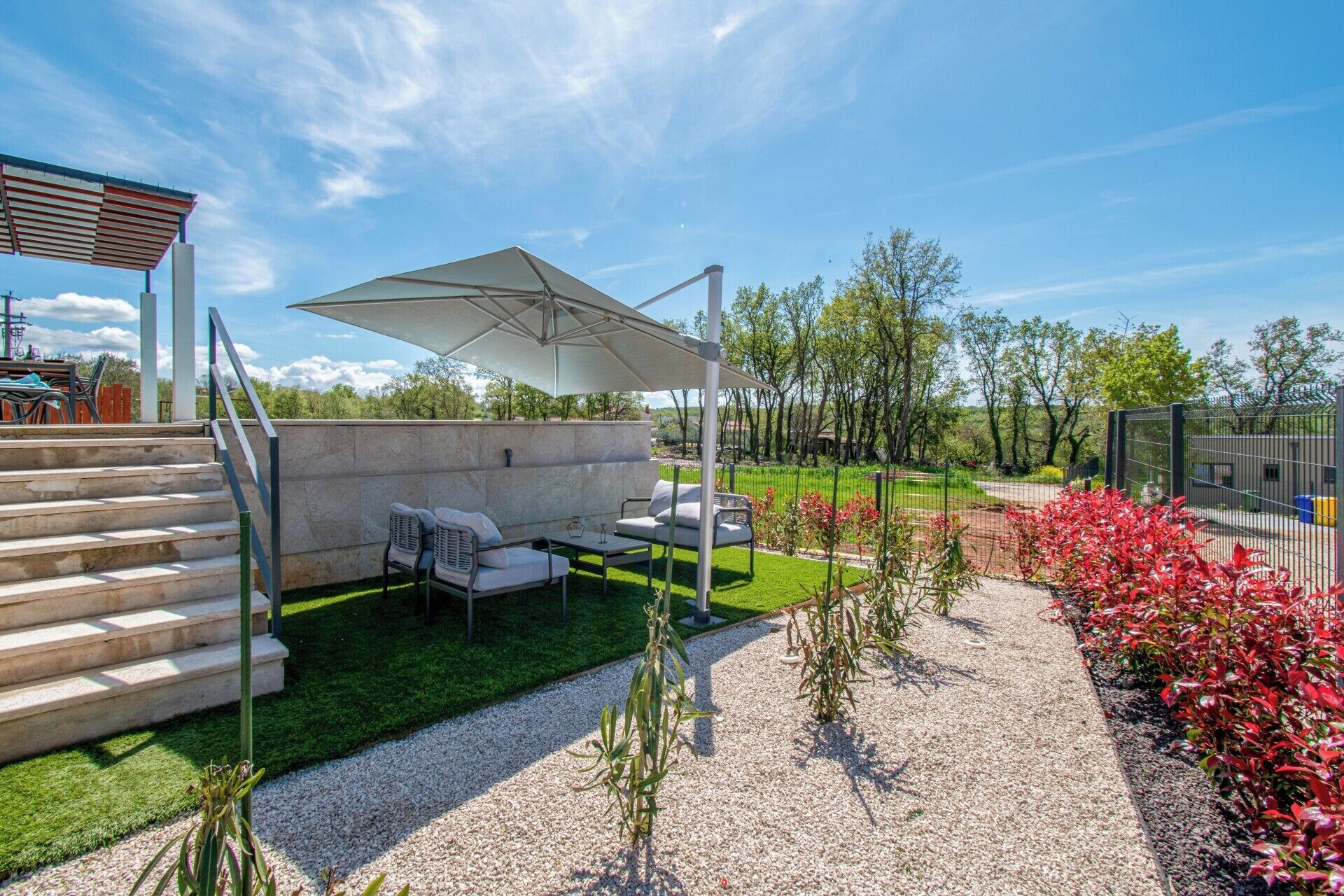 A patio area with outdoor seating, a pergola, and a view of a landscaped garden.