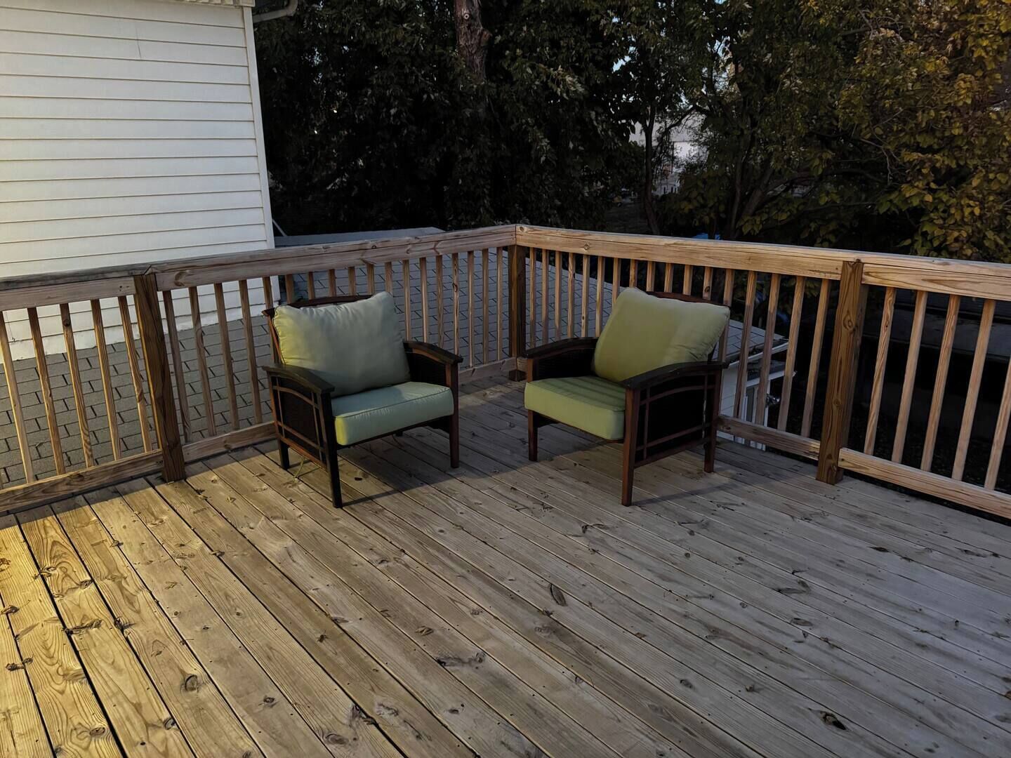 A wooden deck with two chairs and a railing.