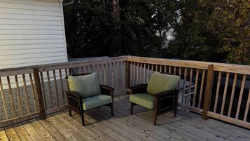A wooden deck with two chairs and a railing.
