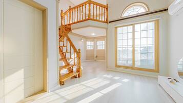 A spacious interior with a wooden staircase, large windows, and a modern design.