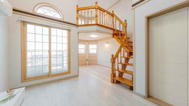 A spacious interior with a wooden staircase, large windows, and a balcony view. - Geoje Peugeot Gomsol Petfriendly Pension (Geoje)