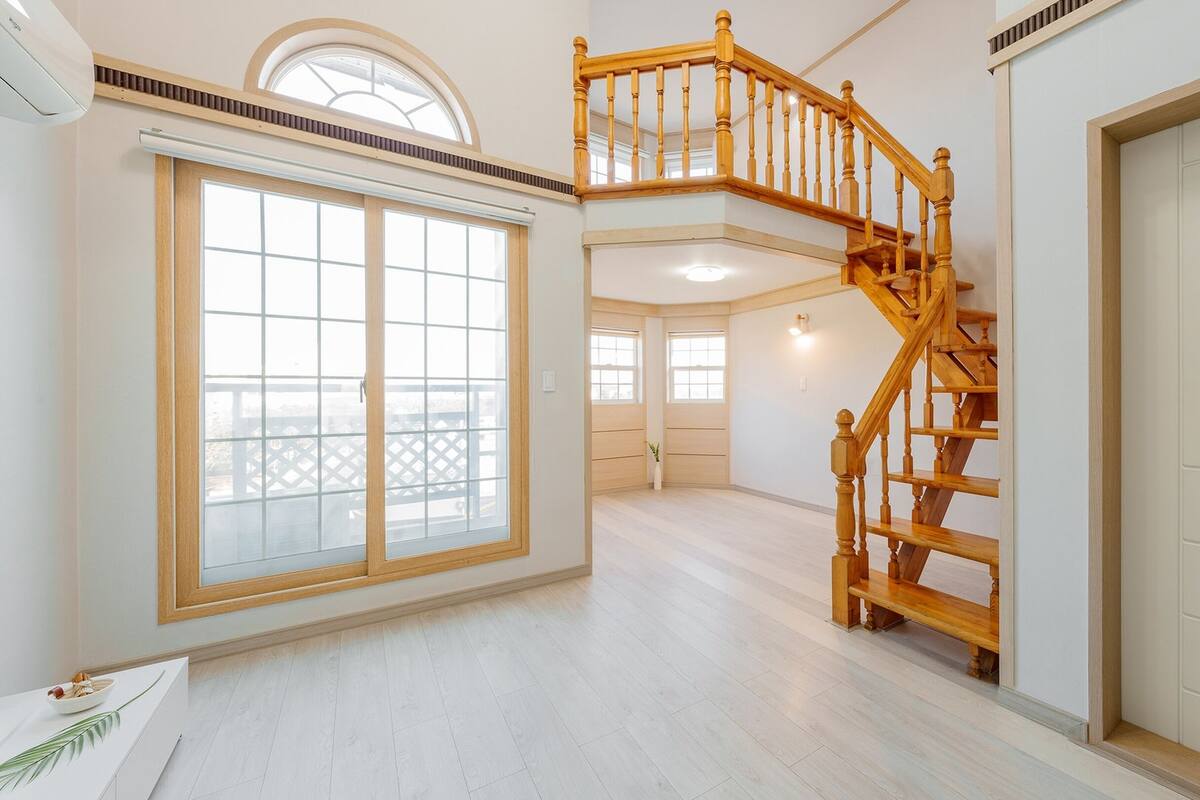 Ein geräumiger Innenraum mit einer Holztreppe, großen Fenstern und Balkonblick.