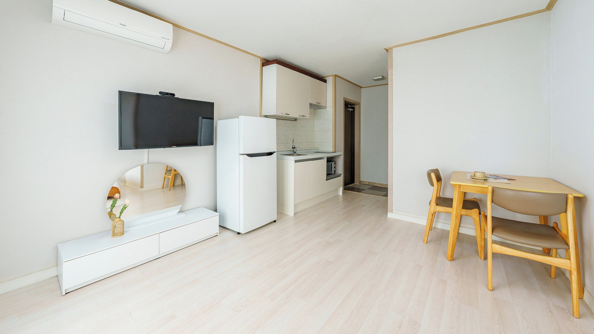 Una cocina moderna con TV integrada, refrigerador y comedor con mesa y sillas.