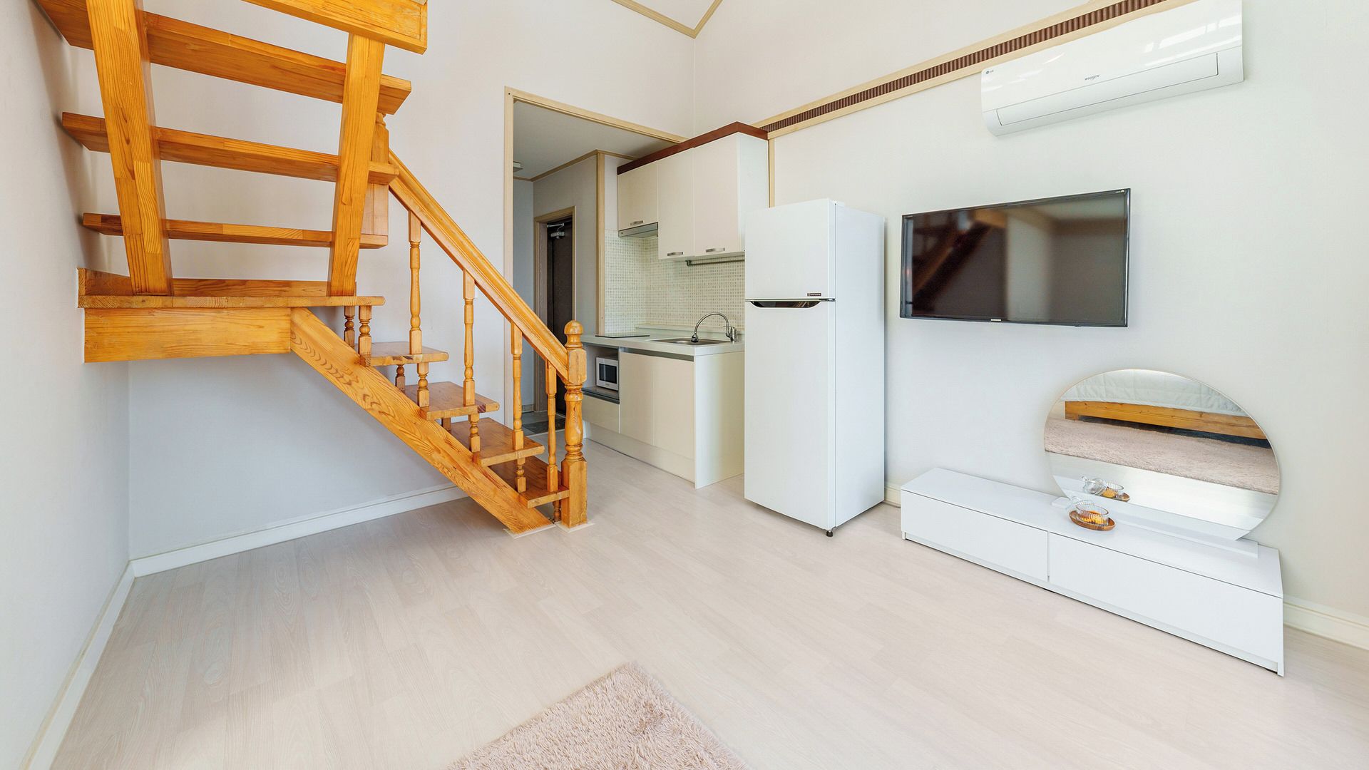 Una cocina moderna con estufa integrada, un refrigerador blanco y un televisor montado en la pared.