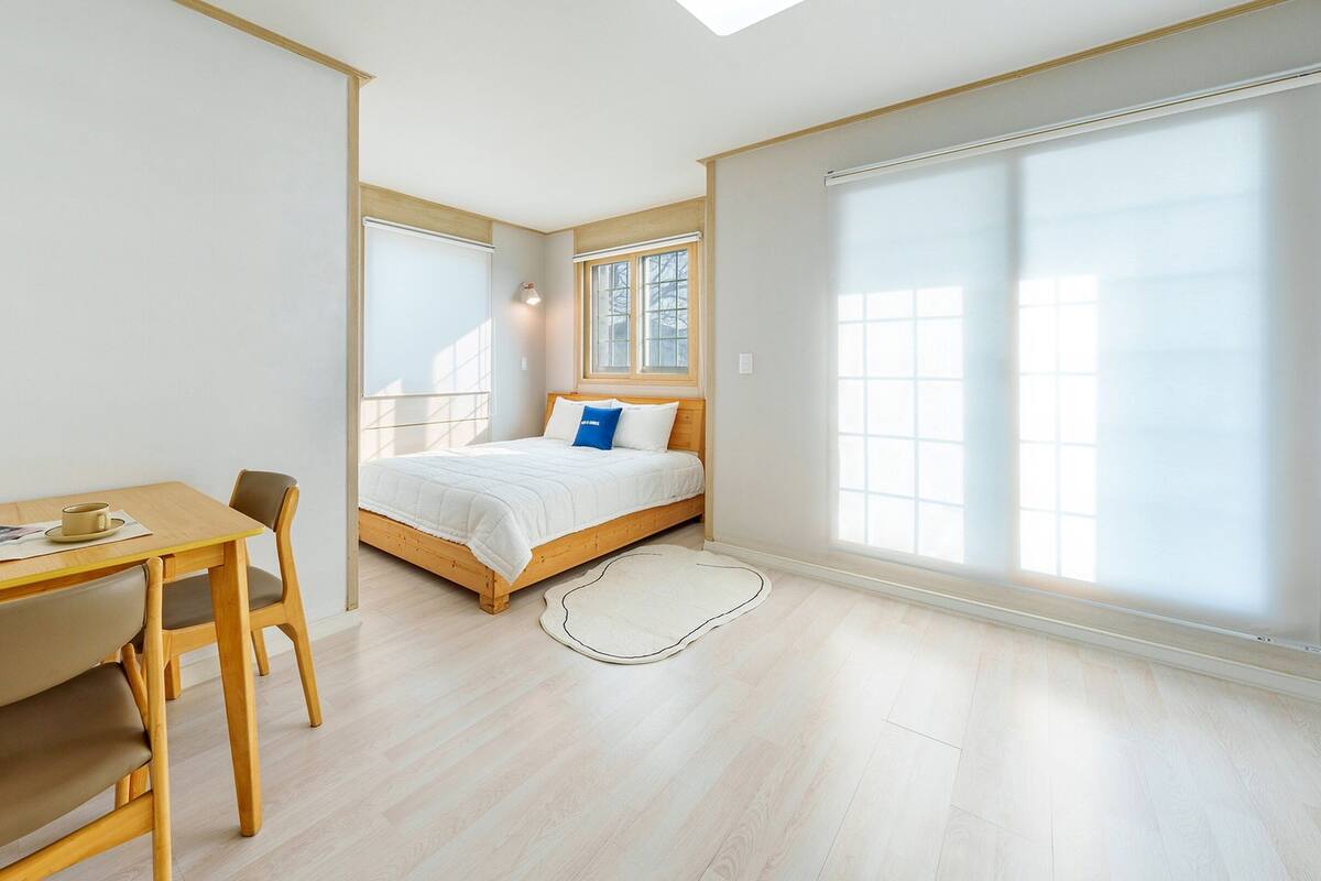 Ein modernes Schlafzimmer mit einem Holzbett, einem Schreibtisch und einem Stuhl.