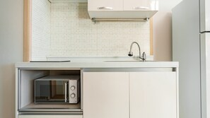 Een keuken met een ingebouwde magnetron, een spoelbak met een kraan en een kast boven de spoelbak.