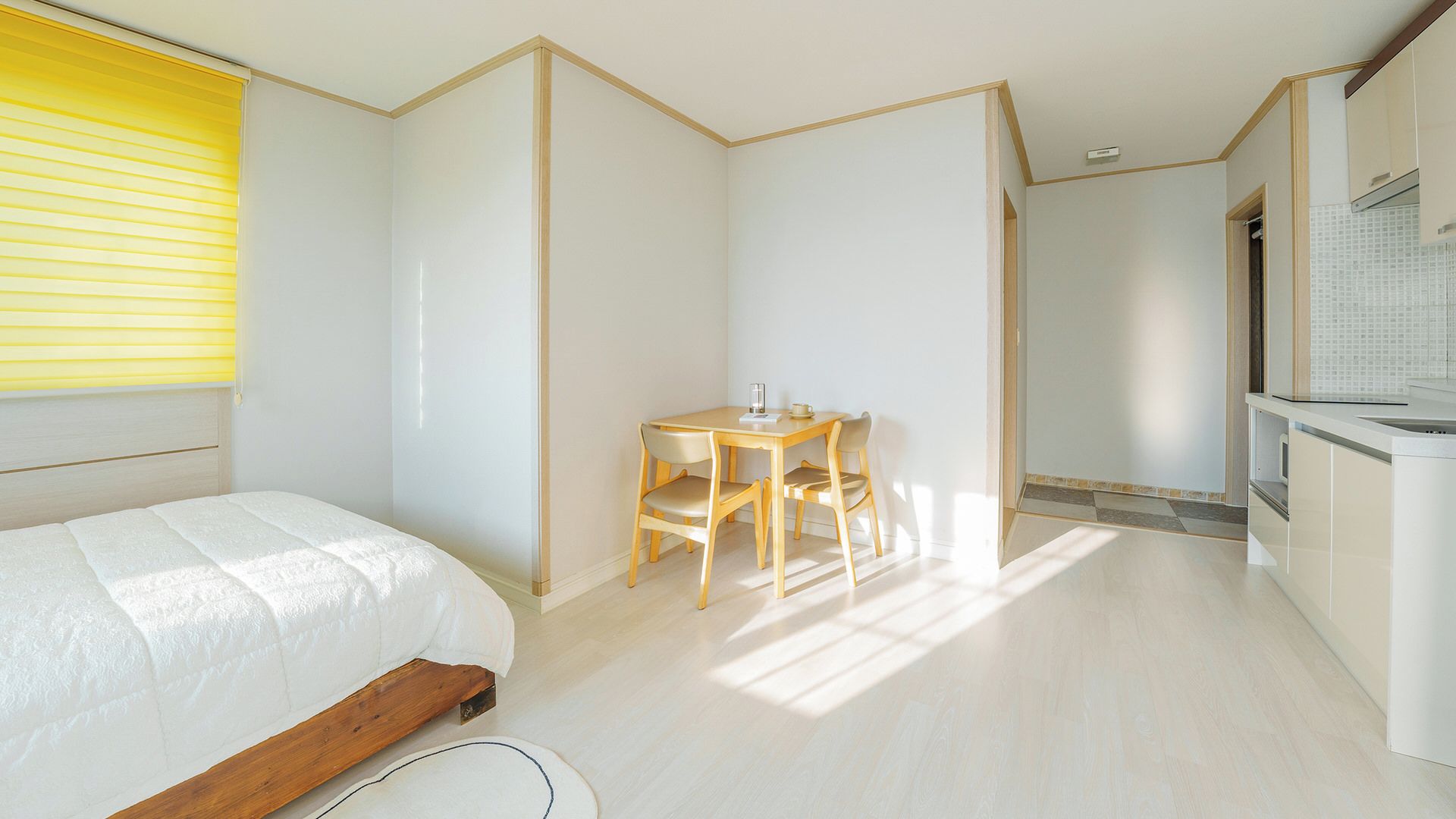 Un dormitorio con una cama, una pequeña mesa con sillas y una zona de kitchenette.