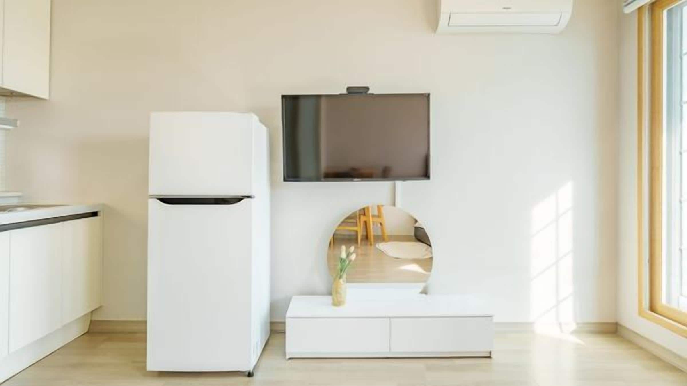 Una cocina moderna con refrigerador integrado, un televisor de pantalla plana montado en la pared y un ventanal que proporciona luz natural.