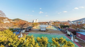 A sports court with a pavilion, surrounded by trees and buildings.