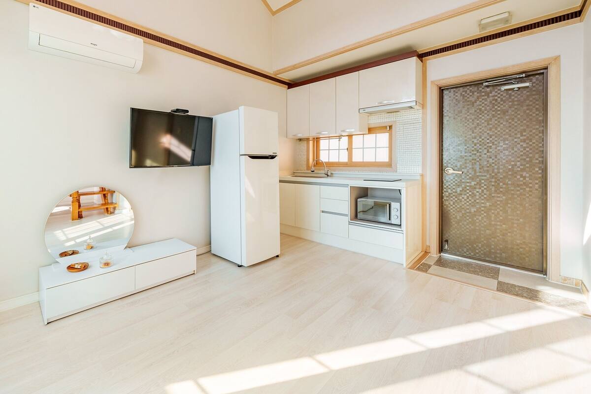 Eine moderne Küche mit Einbauofen, Mikrowelle und Kühlschrank. Über der Arbeitsfläche hängt ein großer Spiegel, an der Wand ist ein Fernseher angebracht.