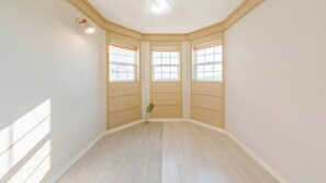 Une pièce d’angle avec trois fenêtres, un plancher en bois et une petite plante.