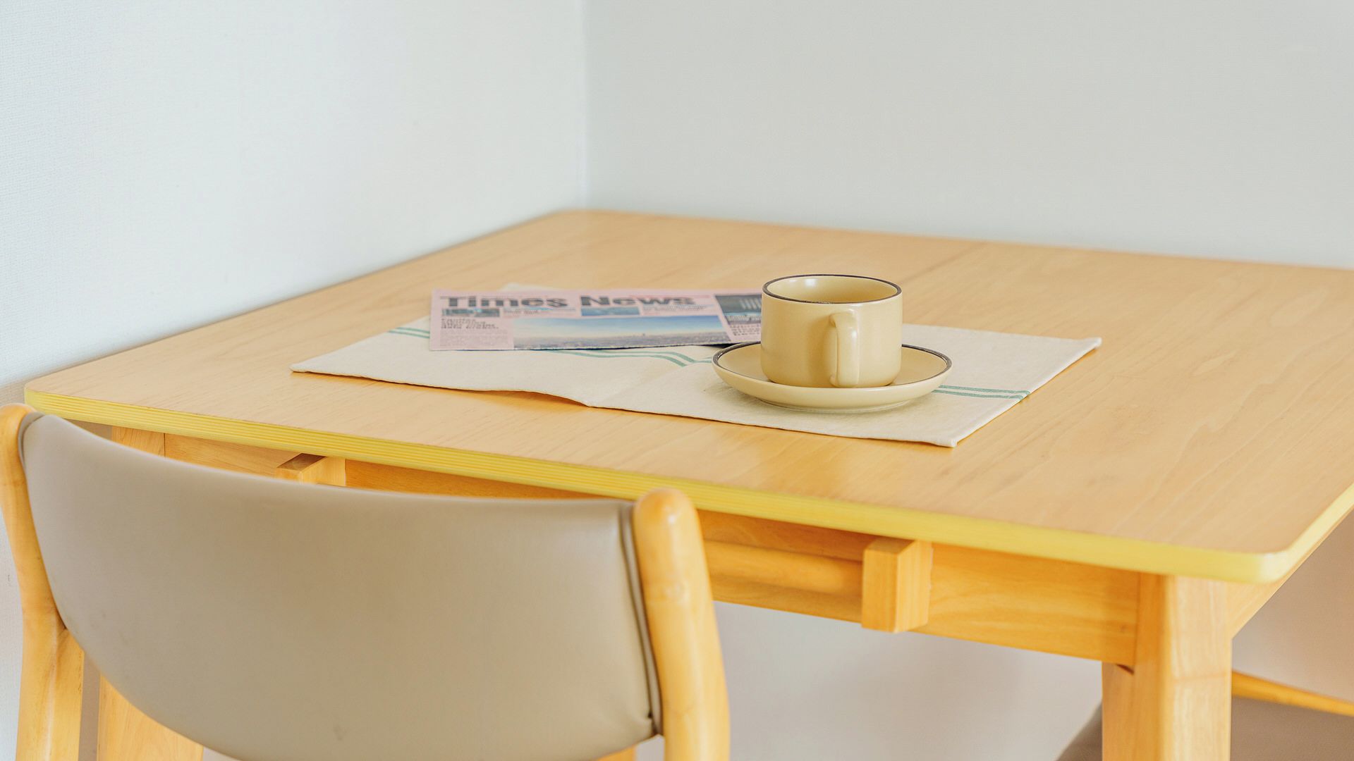 Une petite table en bois, avec un journal, une tasse et une soucoupe.