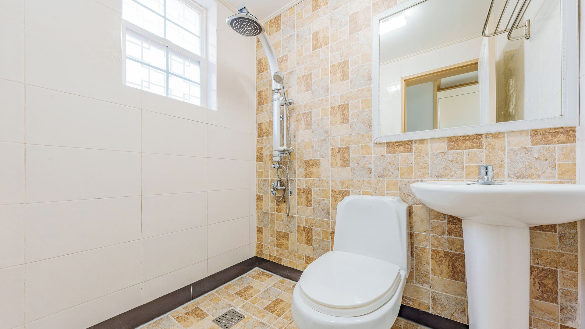 A bathroom with a shower, toilet, sink, and a window.