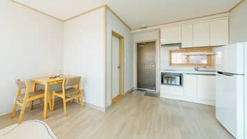 Cocina compacta con muebles blancos, horno empotrado y microondas.