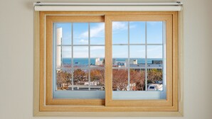 A window with a view of a coastal cityscape, including buildings and trees. - Geoje Peugeot Gomsol Petfriendly Pension (Geoje)