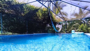 Une piscine d’eau cristalline, avec un hamac et un flotteur gonflable.