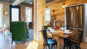 A dining area with a wooden table, black chairs, and a green armchair.