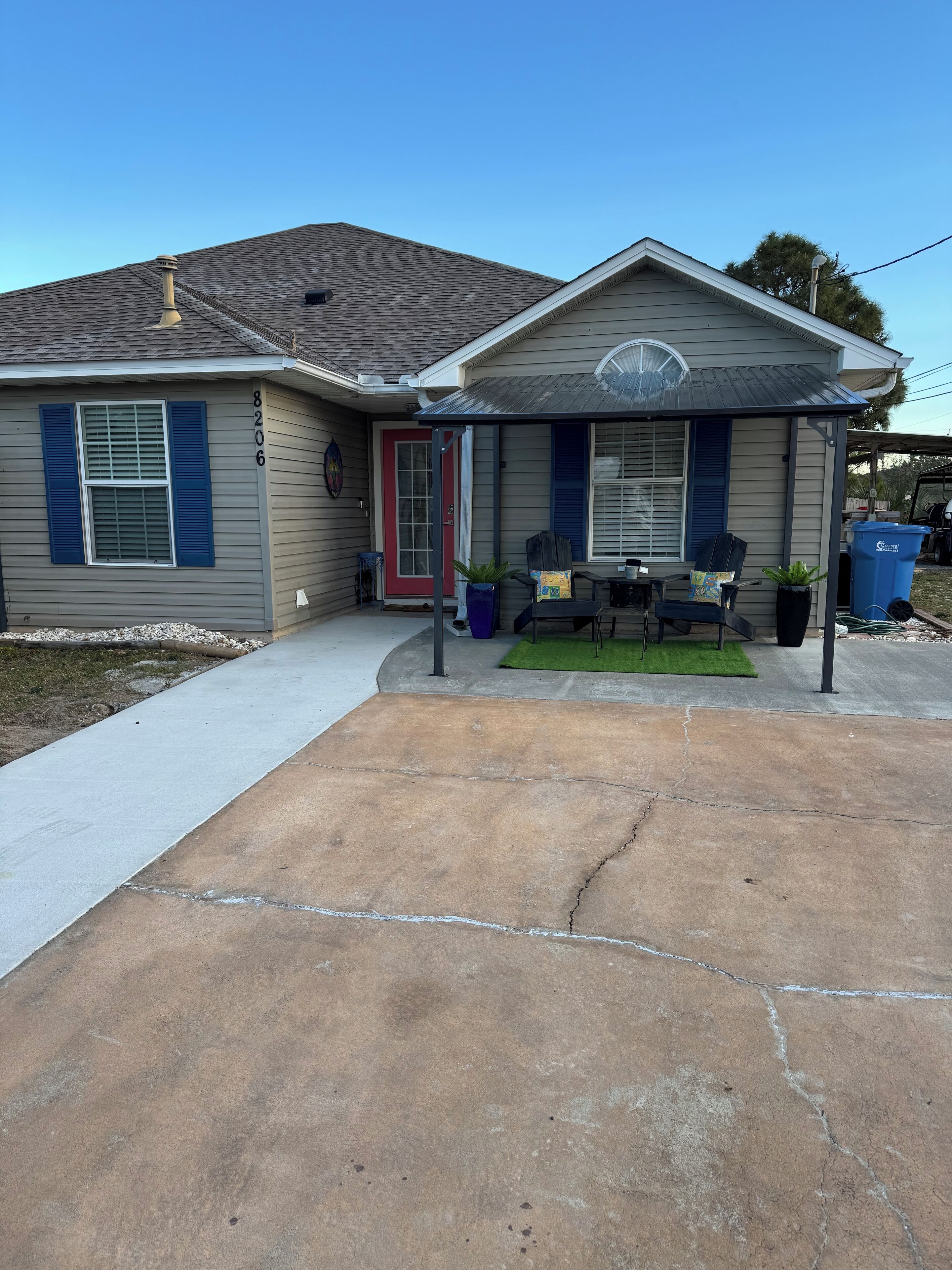 A residential house with a covered porch, a red door, and a mailbox.