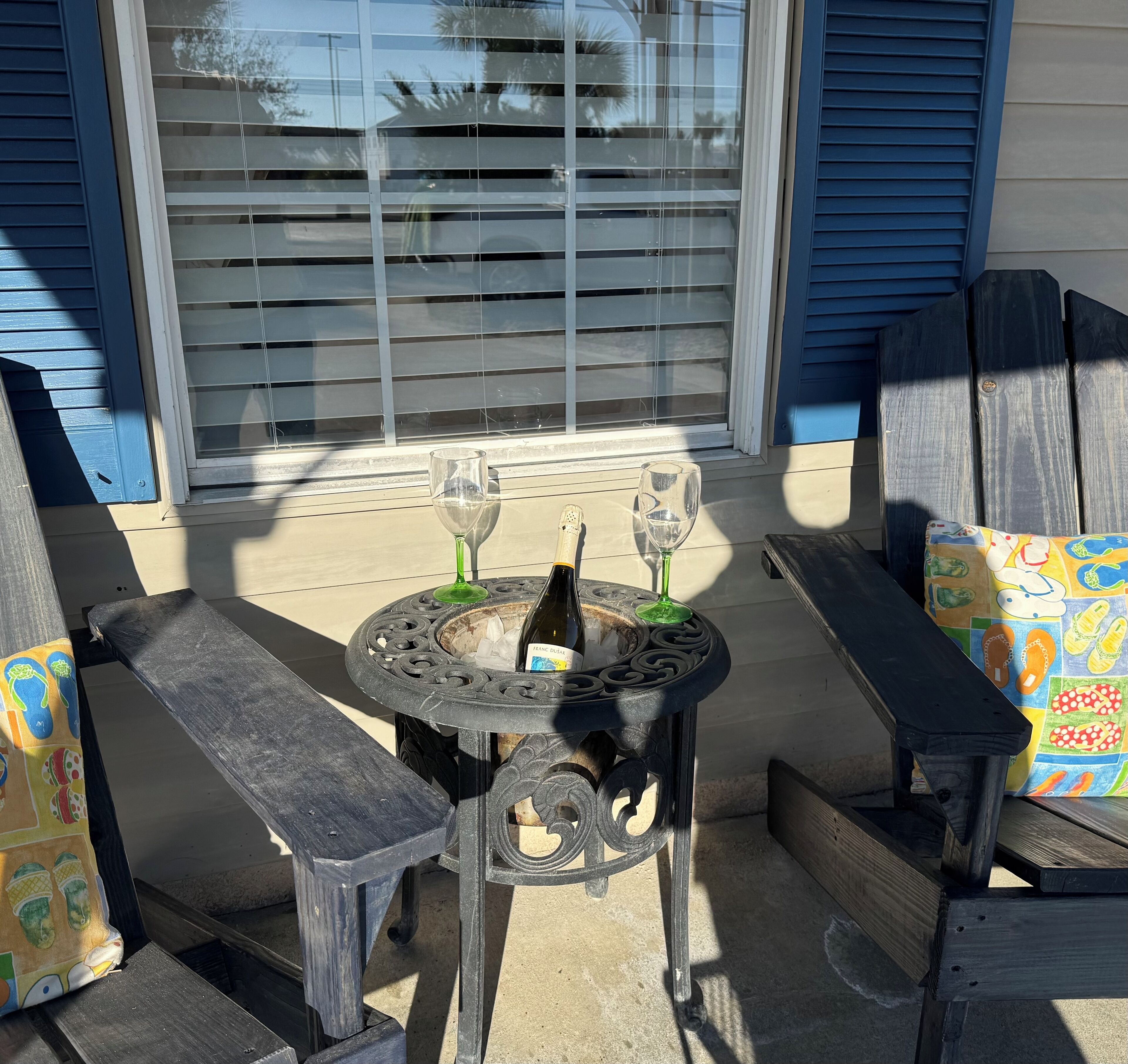 Un patio con una mesa redonda, dos sillas y una botella de vino.