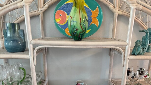 A multi-tiered display shelf with various glassware, plates, and decorative items. - Charming retreat across from Beach access 18 and steps to local attractions.  (Panama City Beach)