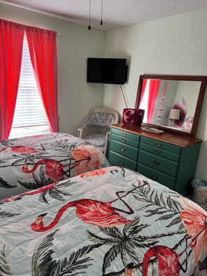A bedroom with two beds, a television, a dresser, and a chair. - Charming retreat across from Beach access 18 and steps to local attractions. (Panama City Beach)