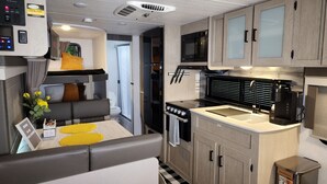 A compact RV kitchen with a stove, microwave, and sink. - The Salem Experience 15 Min from Downtown  (Savannah)