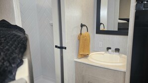 A modern bathroom with a shower, a sink, and a mirror. - The Salem Experience 15 Min from Downtown  (Savannah)
