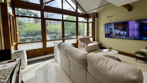 A spacious living room with a large window, a flat-screen TV, and a sofa. - Casa Valparón Porrúa Llanes - Terraces and Views (Porrua)