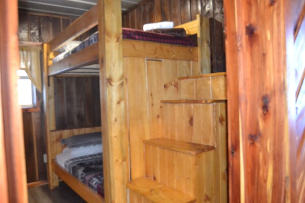 Un lit superposé avec une tête de lit en bois et une étagère au-dessus.