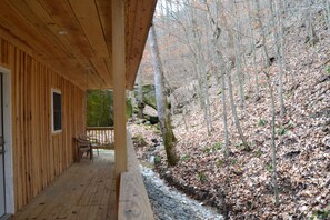 A wooden cabin with a porch, a window, and a chair.