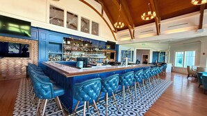 Eine Bar mit einer langen Theke, mehreren Barhocker und einem gemusterten Boden.