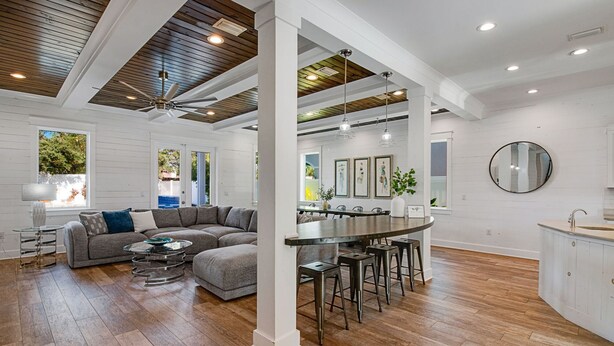 A spacious living area with a large L-shaped sectional sofa, a dining table with bar stools, and a kitchen area with a round island. - 🌅 Saltwater Sunsets | Private Pool & Close to Beach | Dog Friendly* | FREE Excursions ☀️ (Destin)