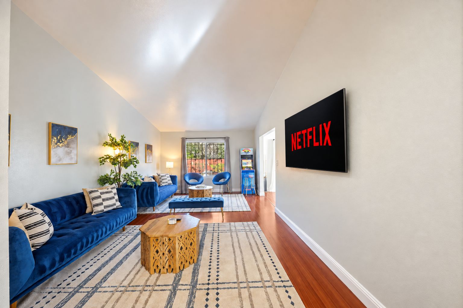 Un salon avec un canapé bleu, une table basse et un logo Netflix sur le mur.